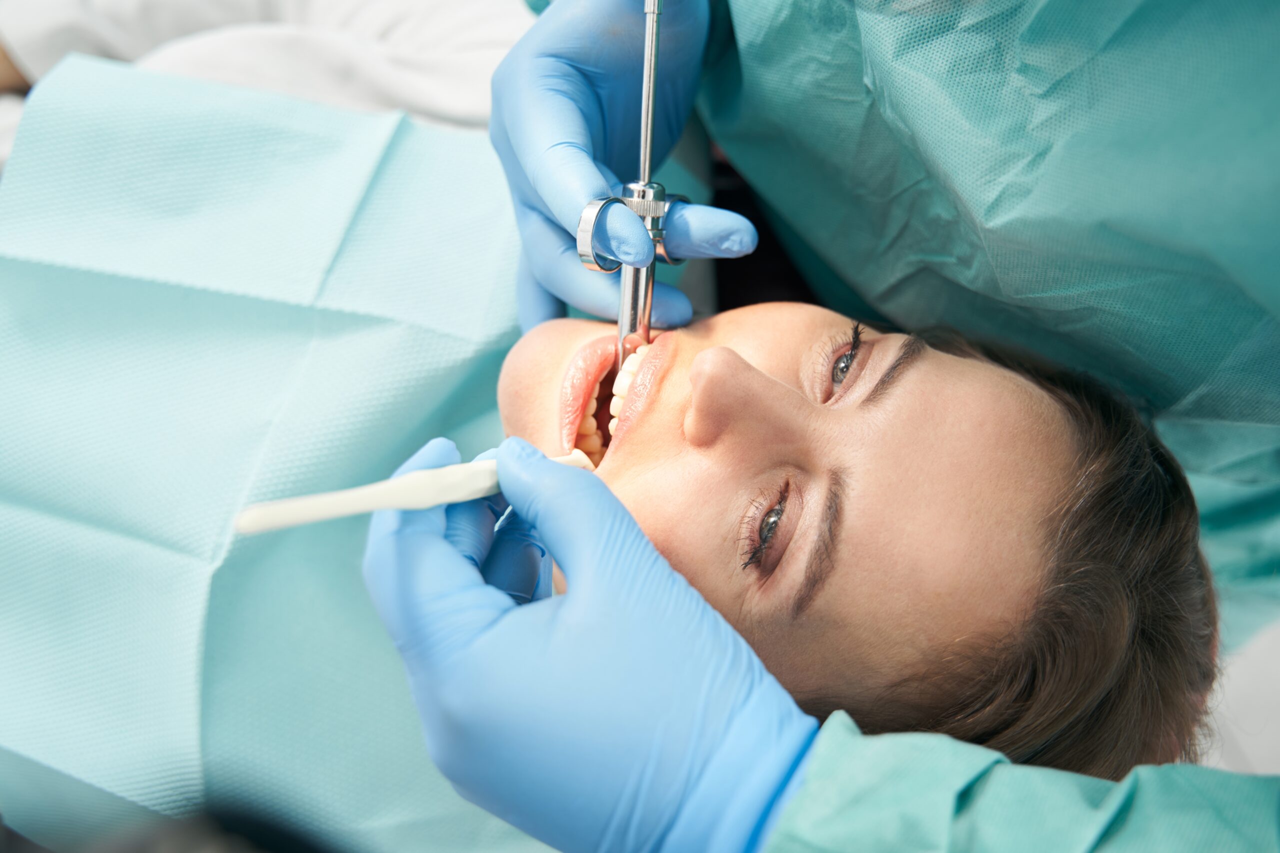 dentist in blue gloves numbing a patient before a root canal